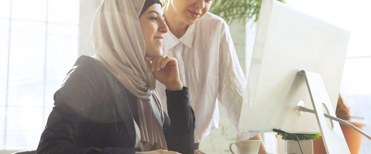 Discussion with colleague. Beautiful arabian businesswoman wearing hijab while working at openspace or office. Concept of occupation, freedom in business area, leadership, success, modern solution.
